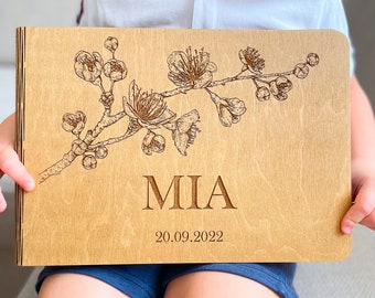 May include: A wooden photo album with a floral design and the name "MIA" engraved on the front. The date "20.09.2022" is also engraved below the name.
