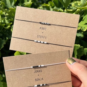 May include: Two sets of friendship bracelets with black and white beads. The first set says "MARC + STEFFI" and the second set says "JONAS + SONJA".