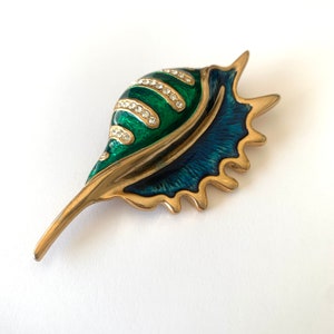 May include: A gold-tone brooch shaped like a seashell with green and blue enamel and clear rhinestones.