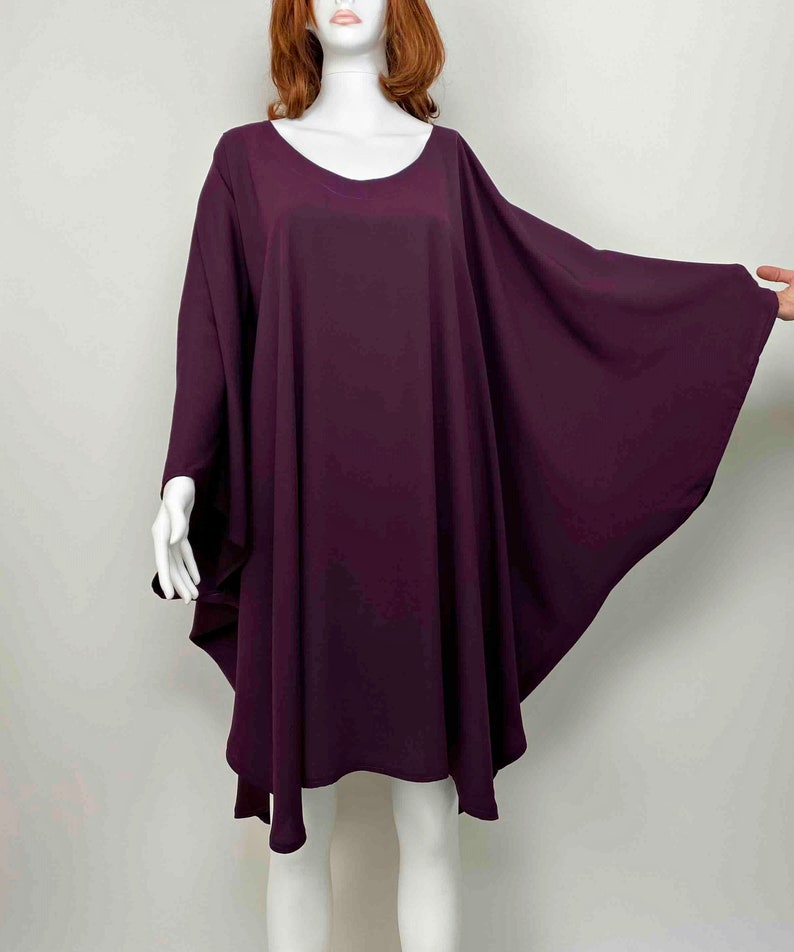 May include: A deep purple, loose-fitting, knee-length dress with a round neckline and long, wide sleeves.
