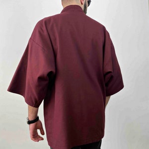 May include: A burgundy short-sleeved kimono-style jacket with a high collar.