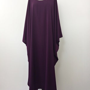 May include: A long, flowing purple kaftan dress with a round neckline and wide sleeves.