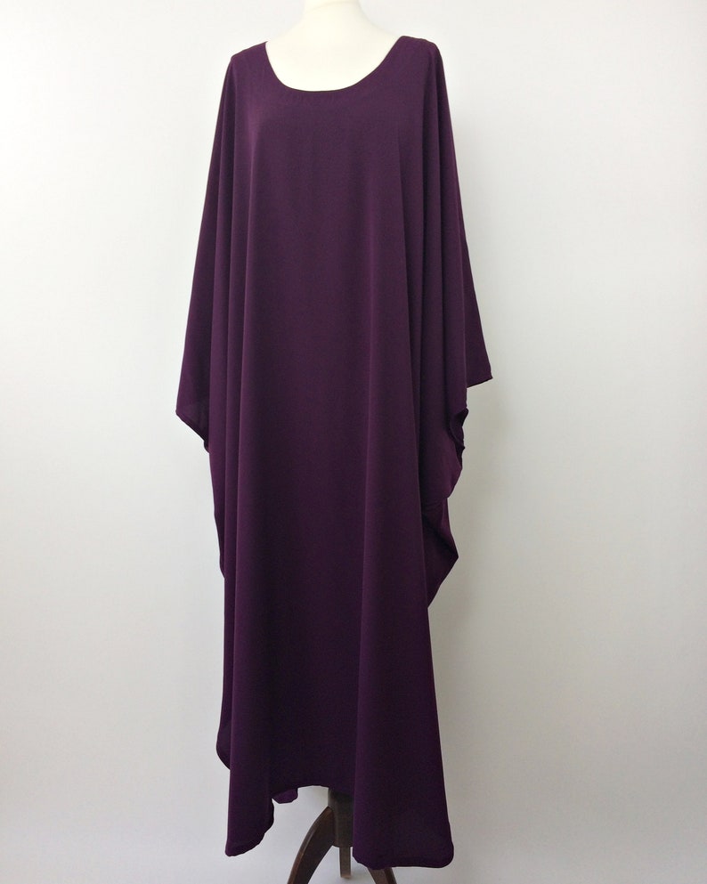 May include: A long, flowing purple kaftan dress with a round neckline and wide sleeves.