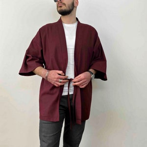 May include: A maroon kimono with long sleeves and a tie belt. The kimono is made of a soft, lightweight fabric and has a relaxed fit.