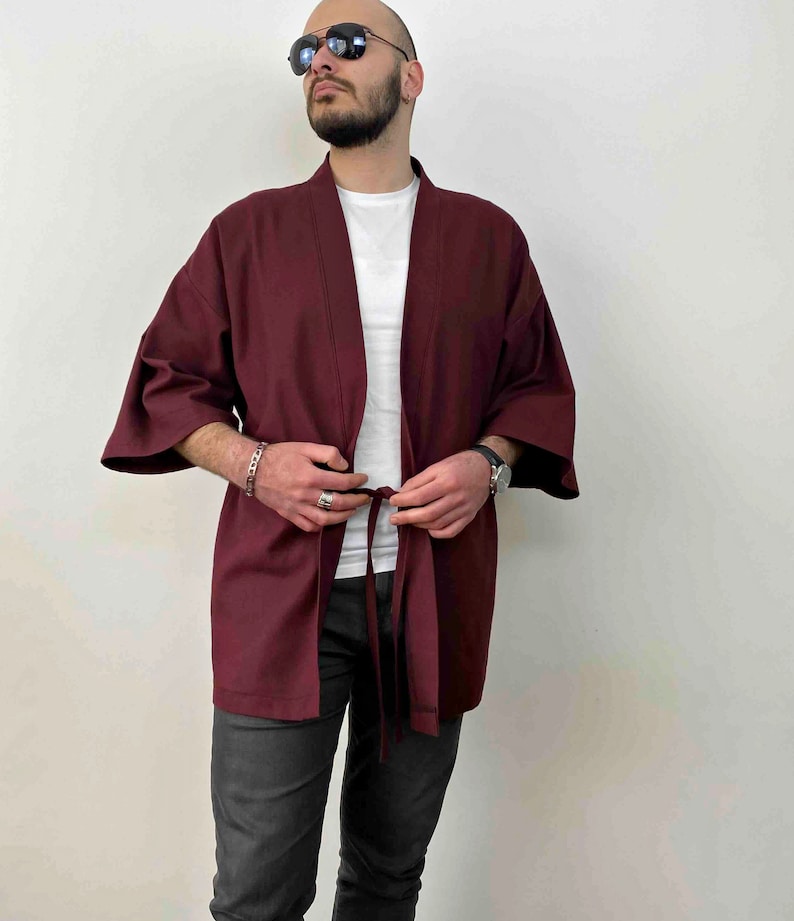 May include: A maroon kimono with long sleeves and a tie belt. The kimono is made of a soft, lightweight fabric and has a relaxed fit.