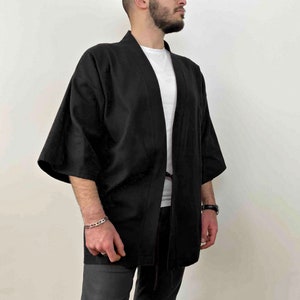 May include: A black kimono-style jacket with long sleeves and a tie closure. The jacket is made of a lightweight fabric and has a relaxed fit.