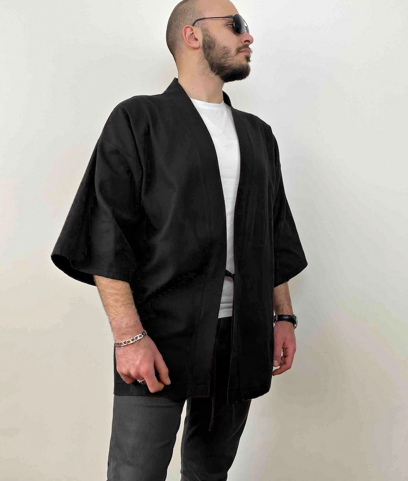 May include: A black kimono-style jacket with long sleeves and a tie closure. The jacket is made of a lightweight fabric and has a relaxed fit.