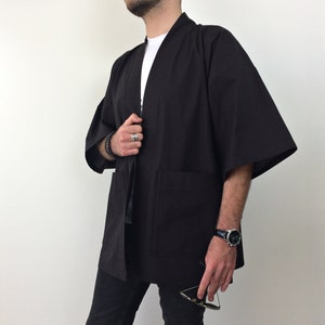 May include: A black kimono with long sleeves and a tie closure. The kimono has two pockets on the front.