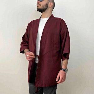 May include: A burgundy kimono with a white undershirt. The kimono has a tie belt and is made of a soft, lightweight fabric.