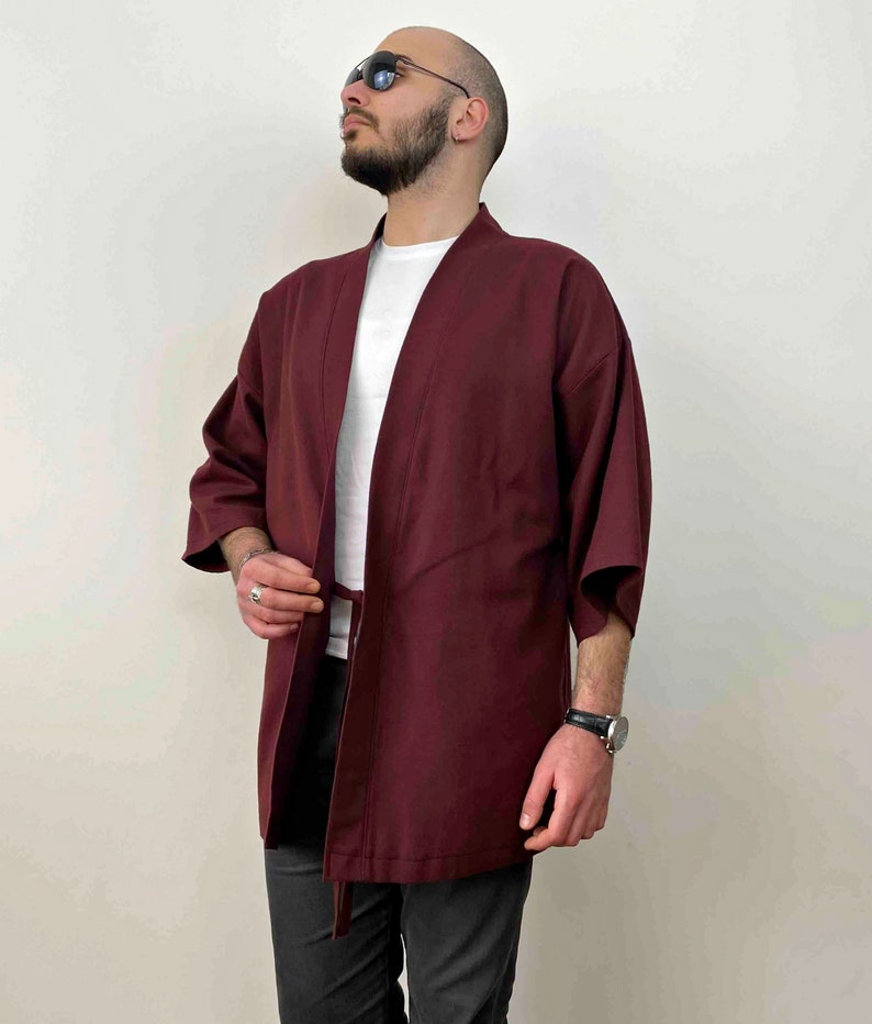 May include: A burgundy kimono with a white undershirt. The kimono has a tie belt and is made of a soft, lightweight fabric.