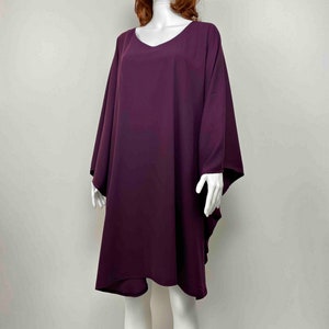 May include: A long, loose-fitting, purple tunic dress with a v-neckline and 3/4 sleeves.