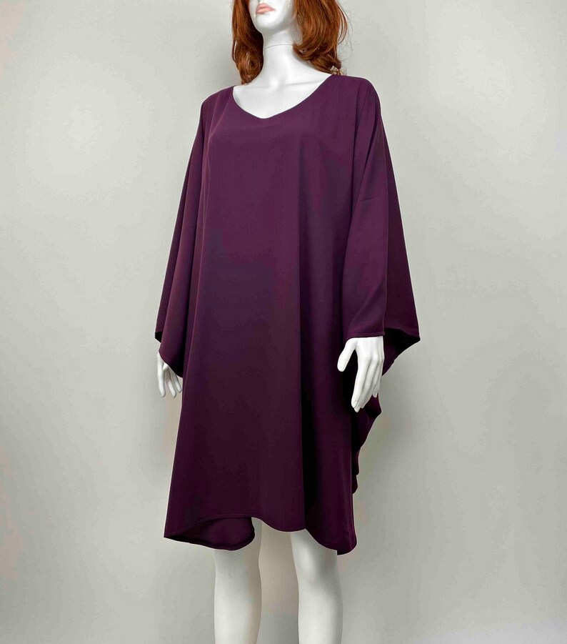 May include: A long, loose-fitting, purple tunic dress with a v-neckline and 3/4 sleeves.
