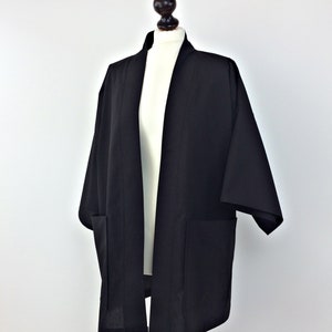 May include: A black kimono with long sleeves and two pockets. The kimono is open in the front and has a simple design.