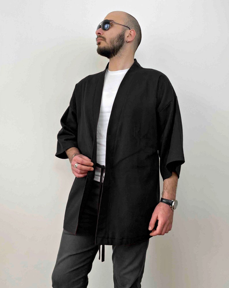 May include: A black kimono-style jacket with a long tie belt. The jacket has a relaxed fit and is made of a soft, lightweight fabric.