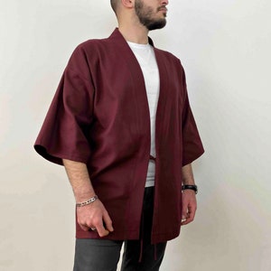 May include: A maroon kimono with a long sleeve and a tie belt. The kimono is made of a soft, lightweight fabric.