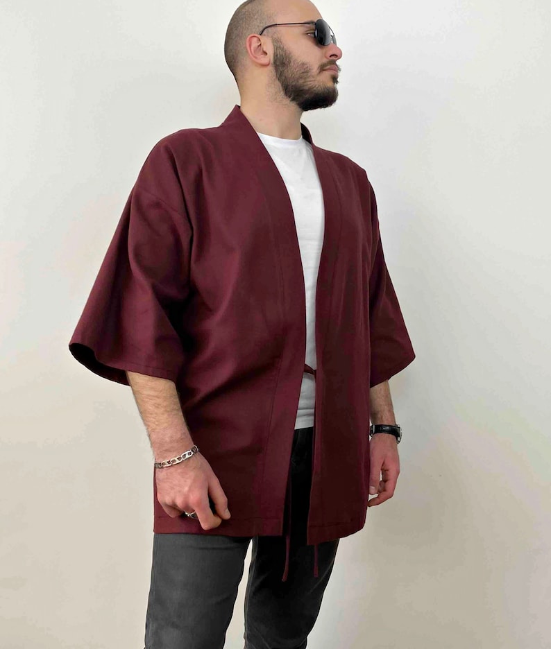 May include: A maroon kimono with a long sleeve and a tie belt. The kimono is made of a soft, lightweight fabric.