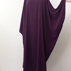 May include: A long, flowing purple kaftan dress with a round neckline and wide sleeves.