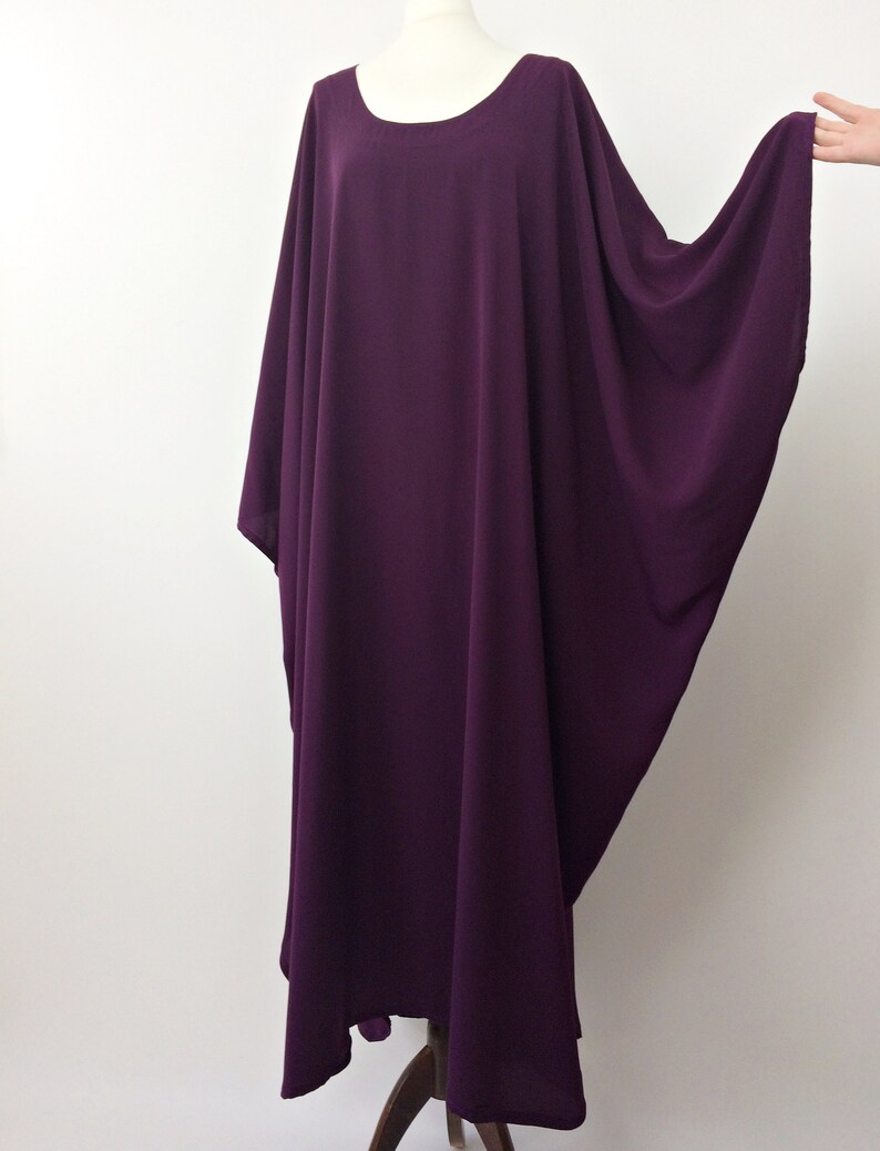 May include: A long, flowing purple kaftan dress with a round neckline and wide sleeves.