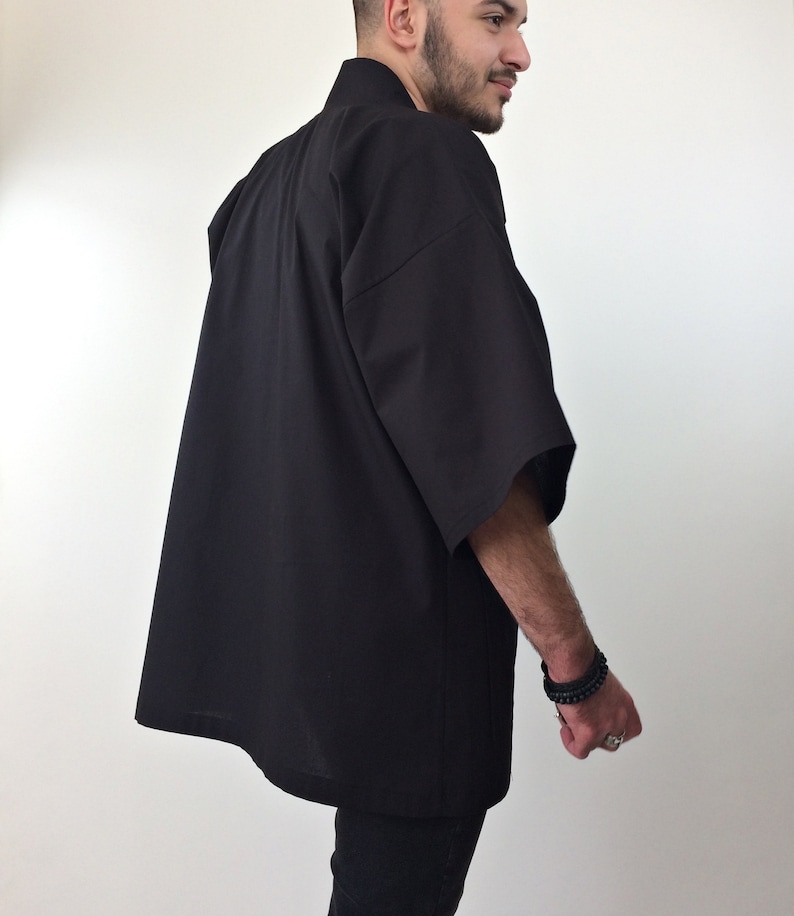 May include: A black short-sleeved kimono-style shirt with a collar. The shirt is made of a lightweight fabric and has a relaxed fit.