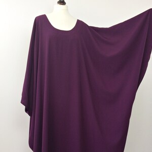 May include: A deep purple, loose-fitting, long-sleeved top with a round neckline.