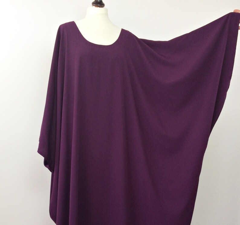 May include: A deep purple, loose-fitting, long-sleeved top with a round neckline.