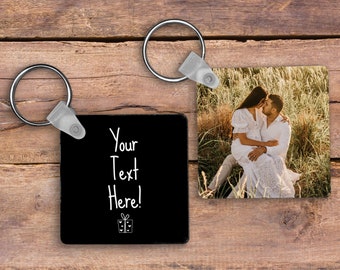 May include: Two square keychains with metal rings. One keychain has a black background with the text "Your Text Here!" and a gift icon. The other keychain displays a photo of a couple kissing in a field.
