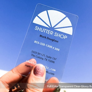 Könnte beinhalten: Eine transparente Plastik-Visitenkarte mit weißem Text und einem weißen Kreisdesign. Der Text lautet "SHUTTER SHOP", "Mark Douglass", "855-320-1300 x 300", "5333 SH 121, Suite 137", "The Colony, TX 75096", "shutter", "mark@1c.com" und "llc.com".