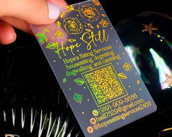 Może przedstawiać: Przejrzysta, matowa wizytówka z holograficzną folią złotą. Wizytówka zawiera tekst "Hope Still" oraz dane kontaktowe Hope's Sitting Services, w tym opiekę nad domem, opiekę nad psami, spacery z psami i opiekę nad kotami. Wizytówka zawiera również numer telefonu, adres e-mail i kod QR.