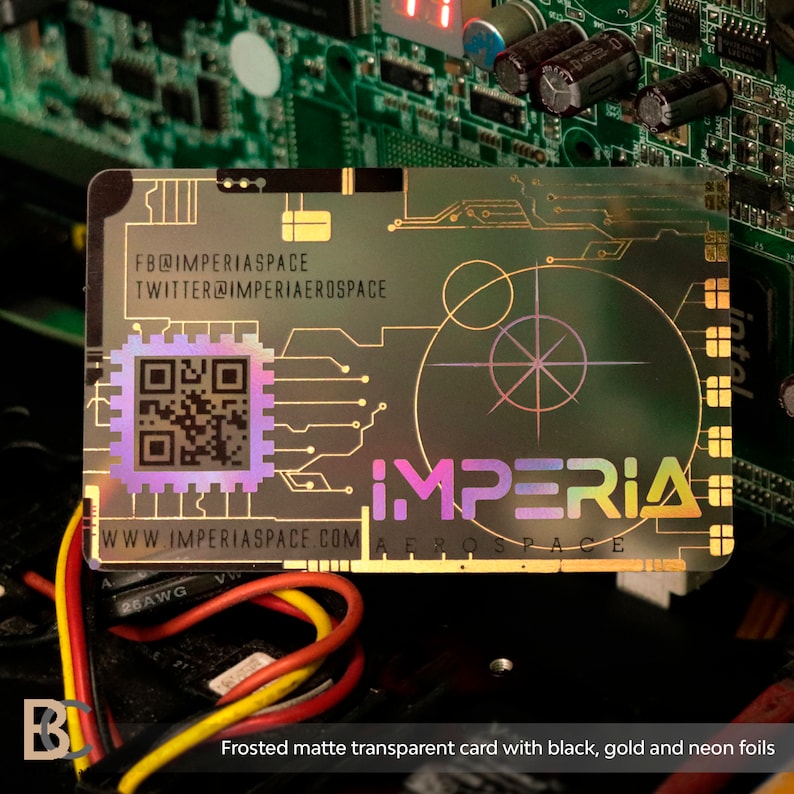 K&ouml;nnte beinhalten: Eine mattierte, transparente Karte mit schwarzen, goldenen und Neon-Folienakzenten. Die Karte zeigt ein holografisches Design mit einem QR-Code, dem Text "IMPERIA AEROSPACE" und der Website-Adresse "WWW.IMPERIASPACE.COM".