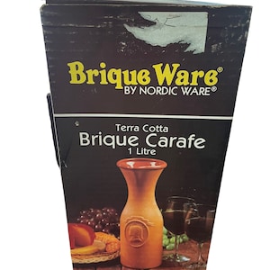 May include: A brown terracotta carafe with a 1-litre capacity, labelled "Brique Carafe" and "Terra Cotta" on a black box with the text "Brique Ware by Nordic Ware".