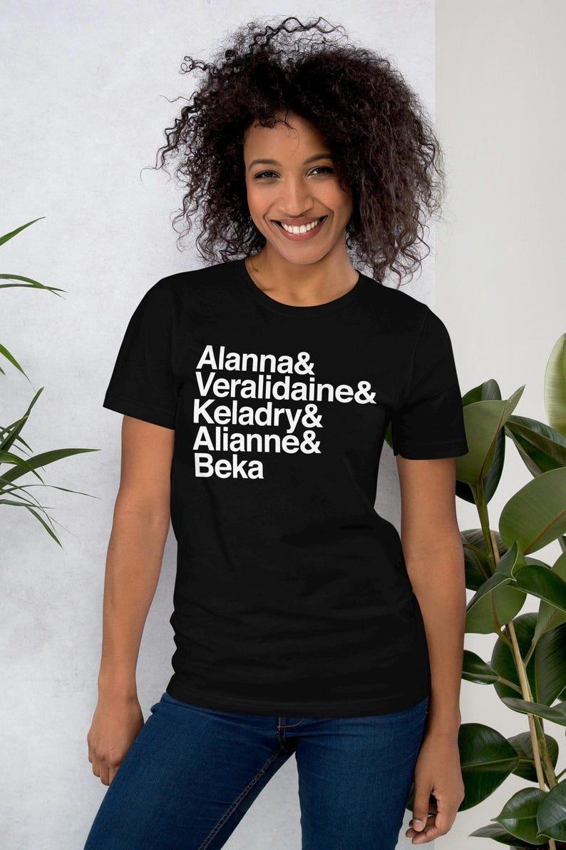 person wearing the black custom shirt with white helvetica text, left aligned, listing vertically characters names from top to bottom: allana &, veralidiane &, keladry &, alianna &, beka