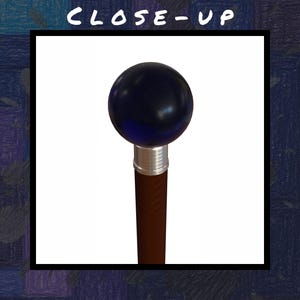 Puede incluir: Primer plano de un bast&oacute;n. El bast&oacute;n tiene un mango esf&eacute;rico azul oscuro, una banda plateada y un eje marr&oacute;n. El texto "CLOSE-UP" est&aacute; en la parte superior de la imagen.