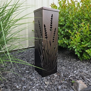 May include: A tall, rectangular, dark bronze metal garden light fixture featuring laser-cut silhouettes of lavender stalks on its front panel. The structure has a flat top and a textured finish, designed to cast light through the cutouts.