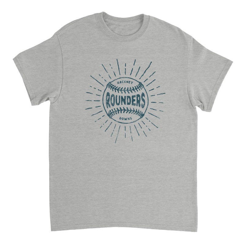May include: A heather gray short-sleeve t-shirt featuring a dark blue graphic of a baseball with the text "HACKNEY ROUNDERS" printed in the center, surrounded by radiating lines that create a sunburst effect on the front of the garment.