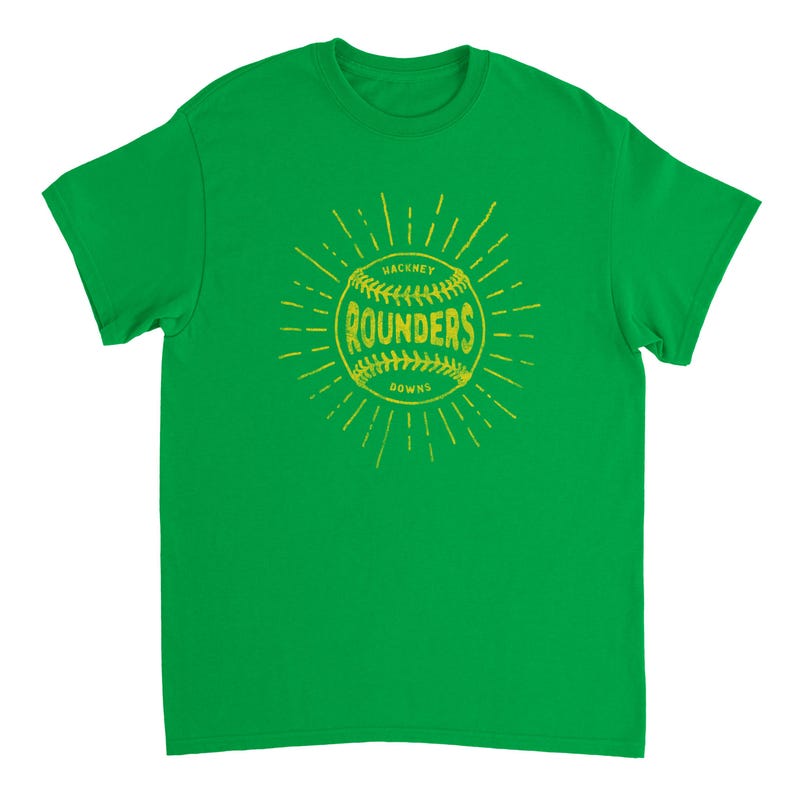 May include: A bright green short-sleeve t-shirt featuring a yellow graphic of a baseball with the text "HACKNEY ROUNDERS DOWNS" printed across the center. The design includes radiating lines extending outward from the ball in a sunburst pattern.