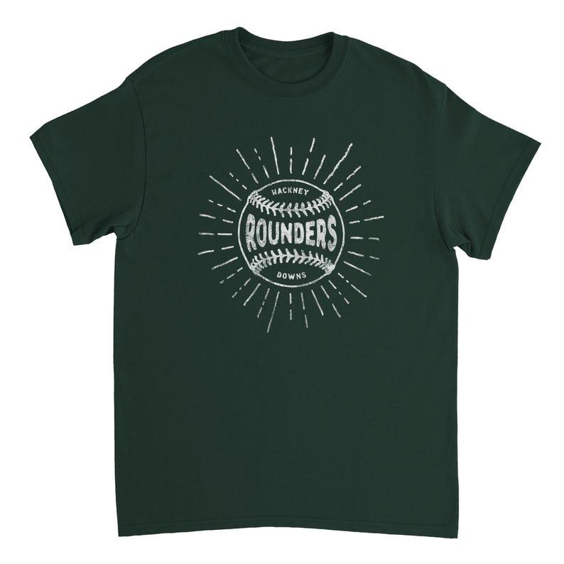 May include: A dark green short-sleeve t-shirt featuring a white graphic of a baseball with the text "HACKNEY ROUNDERS DOWNS" printed across the center. The design includes radiating lines around the ball, creating a sunburst effect on the chest.