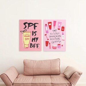 May include: Two pink and white illustrated prints with a skincare theme. The left print features a yellow tube of sunscreen with the text "SPF is my BFF." The right print features a variety of pink and red skincare products with the text "10-step skincare routine queen."