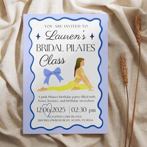 May include: A light purple invitation with a blue border and text that reads "Lauren's Bridal Pilates Class." The invitation includes an illustration of a woman doing Pilates and the date and time of the event.