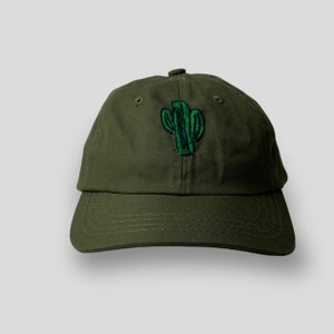 Op de afbeelding: Een groene baseballpet met een geborduurd cactussontwerp.