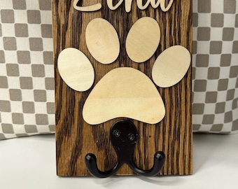 May include: Wooden dog leash hook with a paw print design and the name "Zena" written on it.