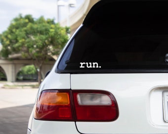 Könnte beinhalten: Ein weißes Auto mit einer schwarzen Heckscheibe und einem weißen Vinyl-Aufkleber mit der Aufschrift "run." auf der Rückseite.