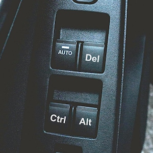 May include: Close-up of a black control panel with four buttons labelled "Auto", "Del", "Ctrl", and "Alt".