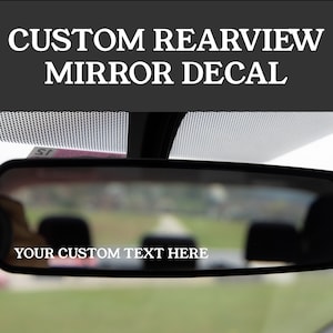 Puede incluir: Un espejo retrovisor negro con una calcoman&iacute;a blanca que dice "YOUR CUSTOM TEXT HERE".