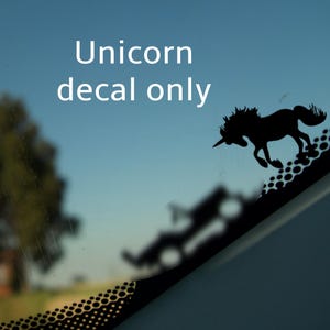 May include: Black silhouette of a unicorn decal on a car window. The decal is on a black and white patterned background. The text "Unicorn decal only" is visible above the decal.