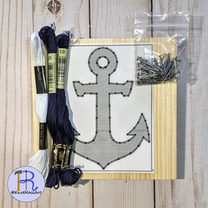 May include: A DIY string art kit featuring a gray anchor design on a white background, mounted on a wooden board. Includes navy blue and white embroidery floss, and a small bag of nails. The kit is designed for crafting.