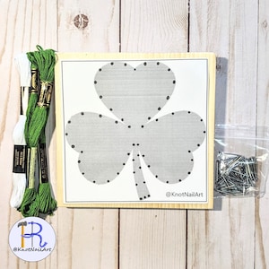 May include: A wooden craft kit featuring a shamrock design with pre-punched holes for stringing. The kit includes green and white embroidery floss, a bag of nails, and instructions.  @KnotNailArt