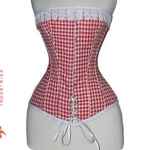 Può includere: Un corpetto in gingham rosso e bianco con bordino in pizzo bianco. Il corpetto ha una schiena con lacci e si stringe in vita.