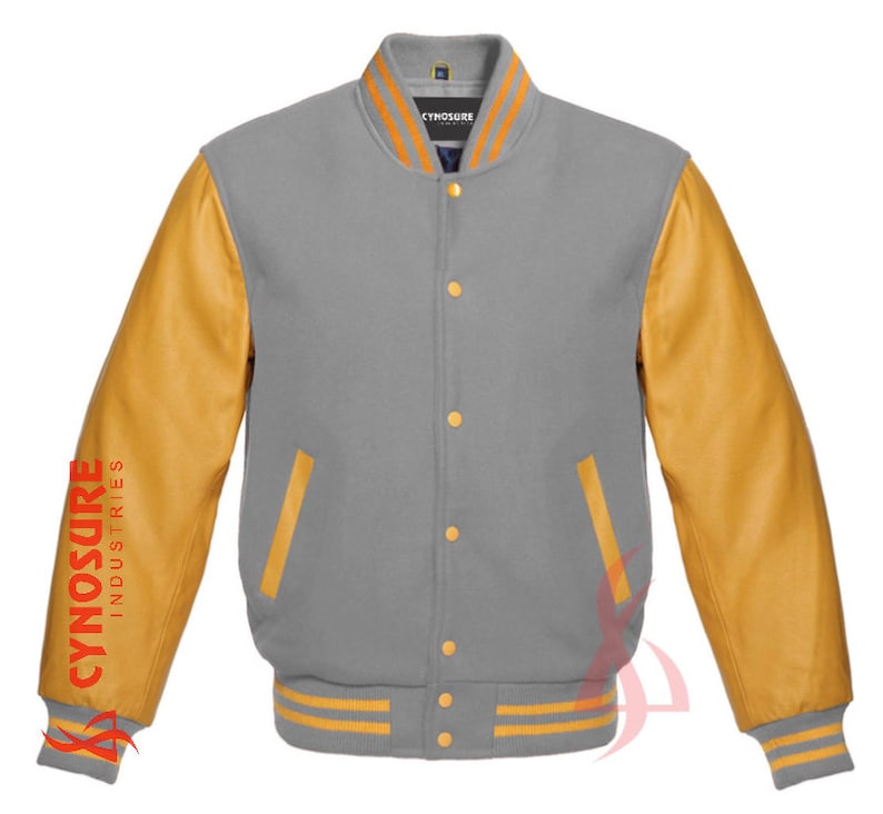 May include: A gray and gold varsity jacket with a ribbed collar and cuffs. The sleeves are made of brown leather and have the text "CYNOSURE INDUSTRIES" printed on the left sleeve. The jacket has a button closure and two pockets.