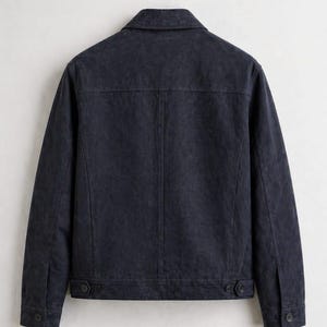 Pu&ograve; includere: Giacca blu navy scuro con colletto classico e polsini con bottoni. La parte posteriore della giacca &egrave; visibile, mostrando un design su misura con cuciture e dettagli dei bottoni. La giacca sembra essere realizzata in un tessuto strutturato.
