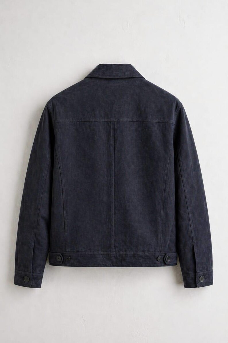 Pu&ograve; includere: Giacca blu navy scuro con colletto classico e polsini con bottoni. La parte posteriore della giacca &egrave; visibile, mostrando un design su misura con cuciture e dettagli dei bottoni. La giacca sembra essere realizzata in un tessuto strutturato.